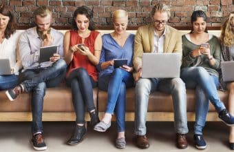 People sitting on a sofa with devices in hand